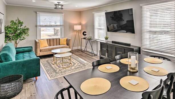 A modern living room with a green sofa, a dining table with placemats, and a large TV on the wall. - ~ 7 Mi to Downtown! Nashville Home Rental (Nashville)