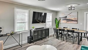 A modern living room with a dining area, featuring a TV, a cabinet, and a dining table with chairs. - ~ 7 Mi to Downtown! Nashville Home Rental (Nashville)