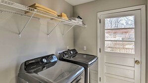 A laundry room with two front-loading washers and dryers, a metal shelf above holding folded towels, and a door with a window view. - ~ 7 Mi to Downtown! Nashville Home Rental (Nashville)