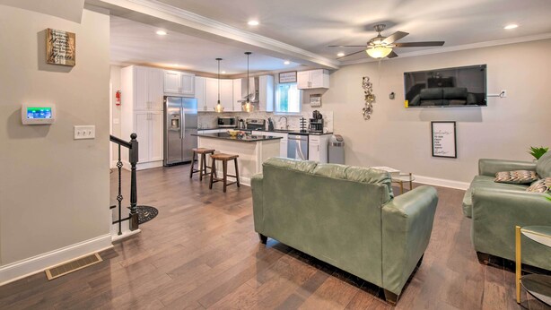 A modern kitchen with white cabinets, a central island, and a dining area with a green sofa.
