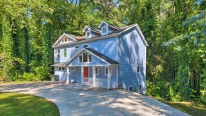 A two-story house with a front porch, surrounded by a wooded area.