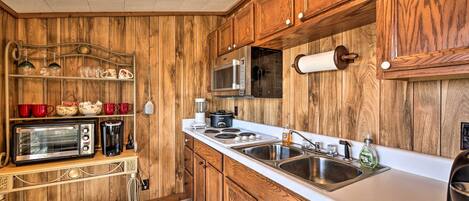 A kitchen with wooden cabinets, a microwave, a toaster, and a sink.