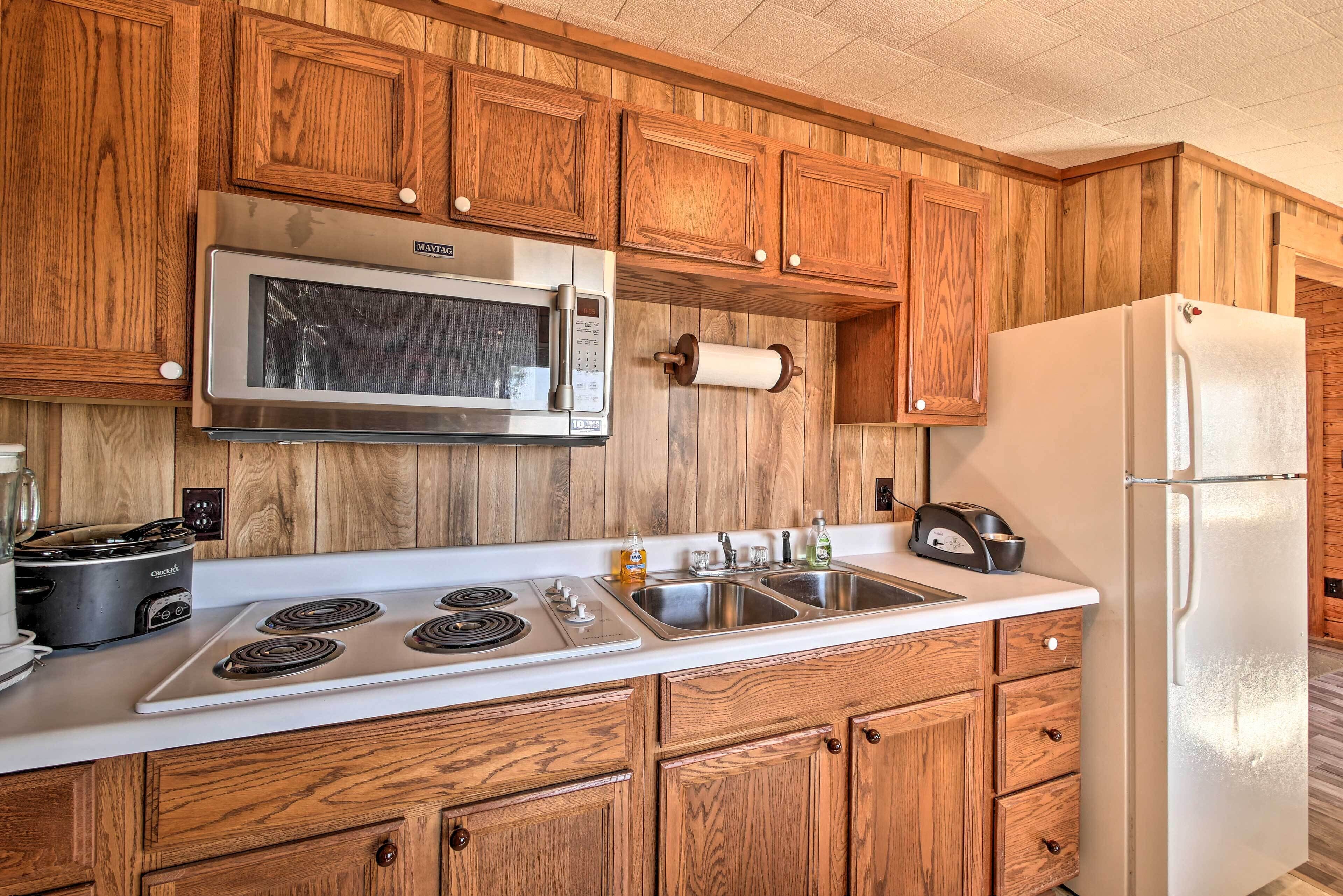 A kitchen with wooden cabinets, a stainless steel microwave, a stove, and a refrigerator.