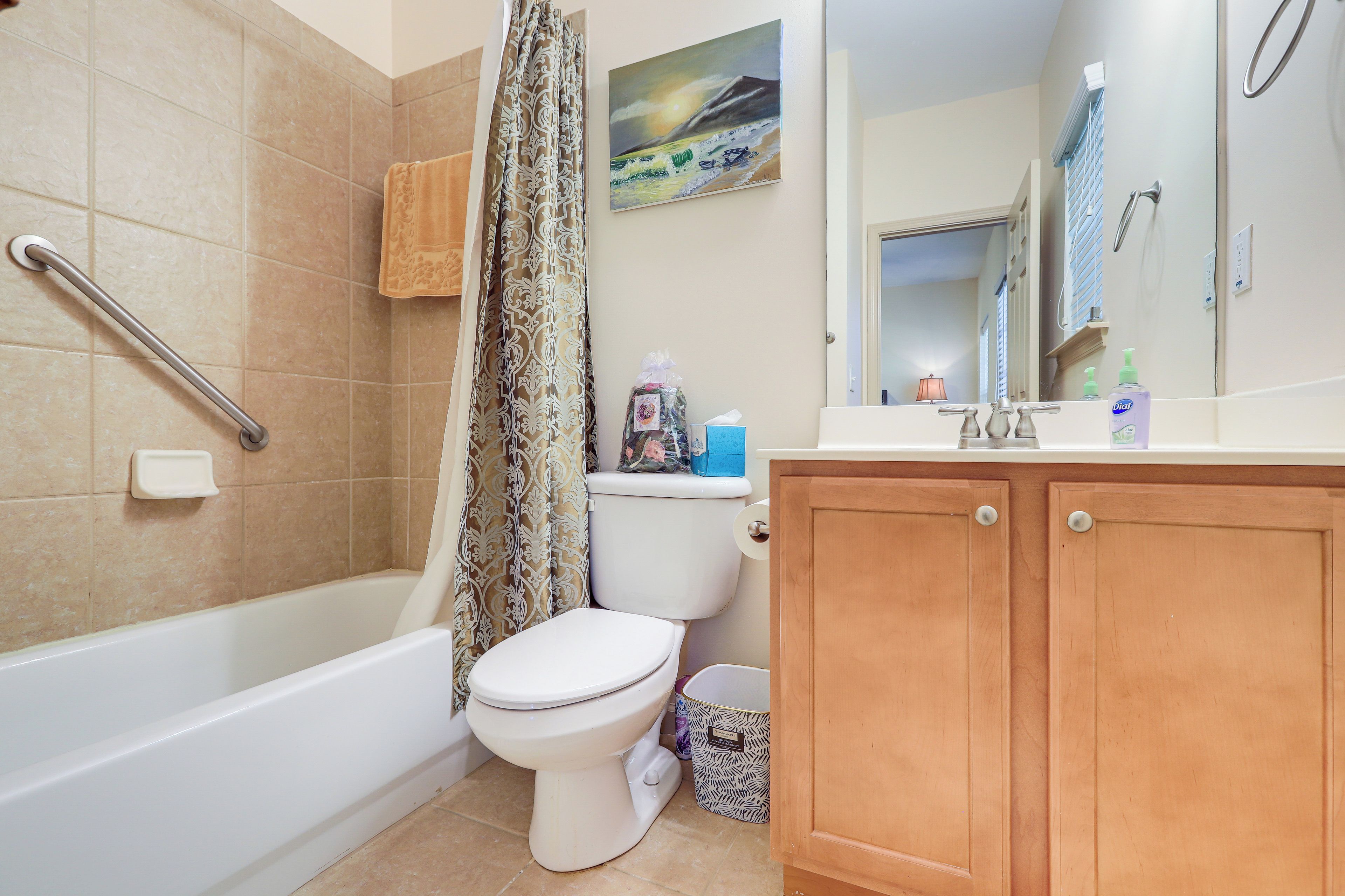 Une salle de bain avec une baignoire, des toilettes, un rideau de douche et des meubles en bois.