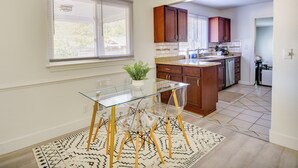Una cocina moderna con armarios de madera, una mesa de comedor de vidrio y una planta en maceta.