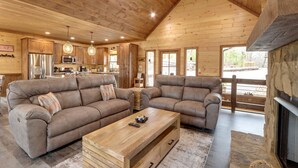 Un vaste espace de vie comprenant deux canapés en cuir, une table basse en bois et une cheminée en pierre.