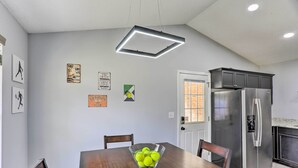 Una cucina moderna con un frigorifero in acciaio inossidabile, un tavolo da pranzo in legno con una ciotola piena di palline da tennis e decorazioni a parete tra cui cimeli sportivi.
