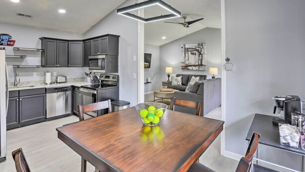 Una cucina moderna con mobili scuri, elettrodomestici in acciaio inossidabile e un'area pranzo con tavolo in legno.