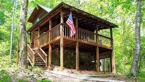 Eine Holzhütte mit Veranda, Treppe und einer amerikanischen Flagge.