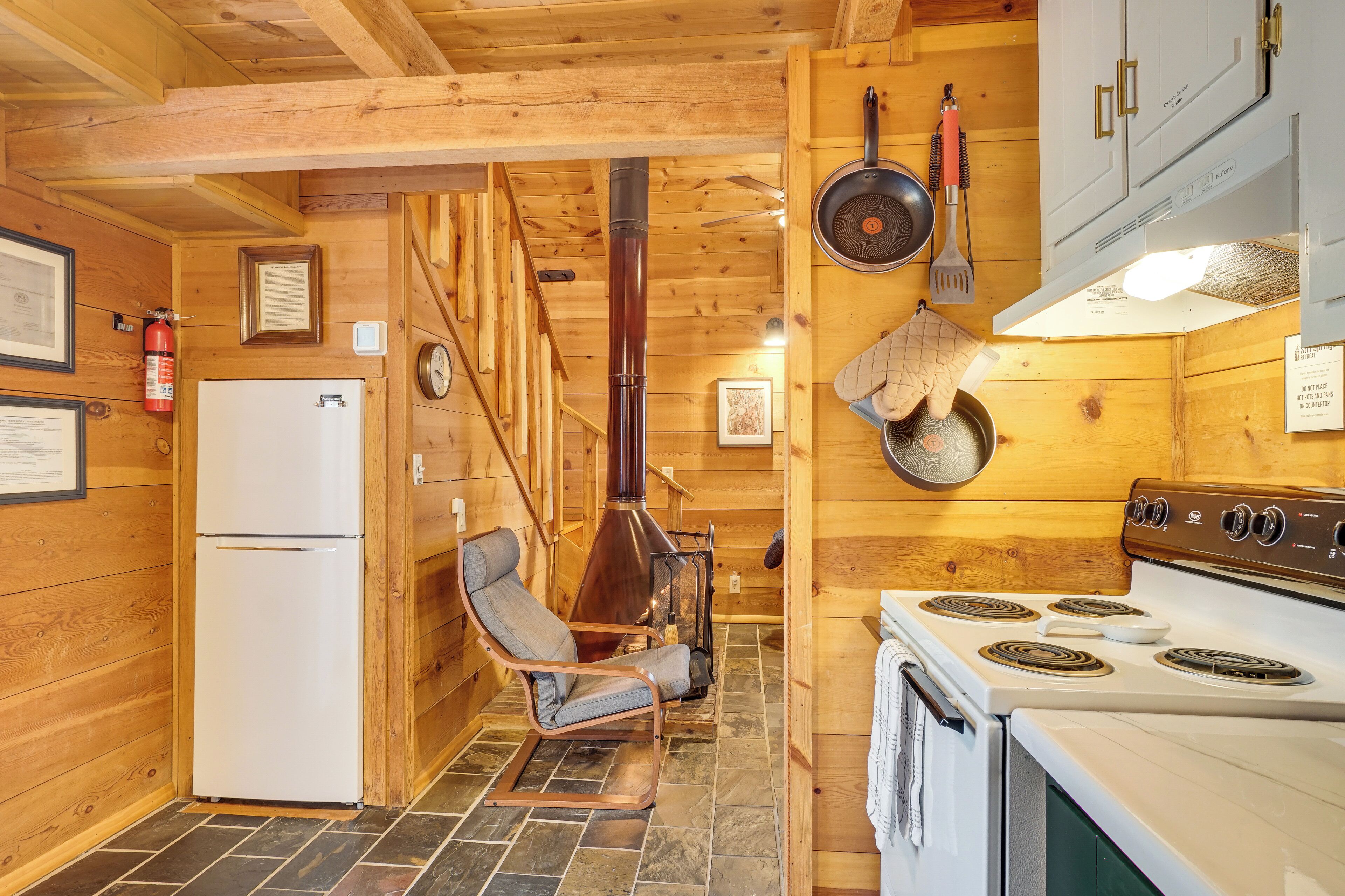 A wooden interior with a kitchen area including a stove, oven, and a chair.
