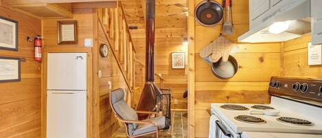 A wooden interior with a kitchen area including a stove, oven, and a chair.