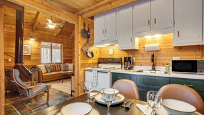 Ein gemütliches Blockhaus-Interieur mit Essbereich, Holzwänden, Kamin und einer kleinen Küche.