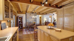 Une cuisine spacieuse dotée de meubles en bois, d’un grand îlot central et d’un coin repas avec des chaises et une table.