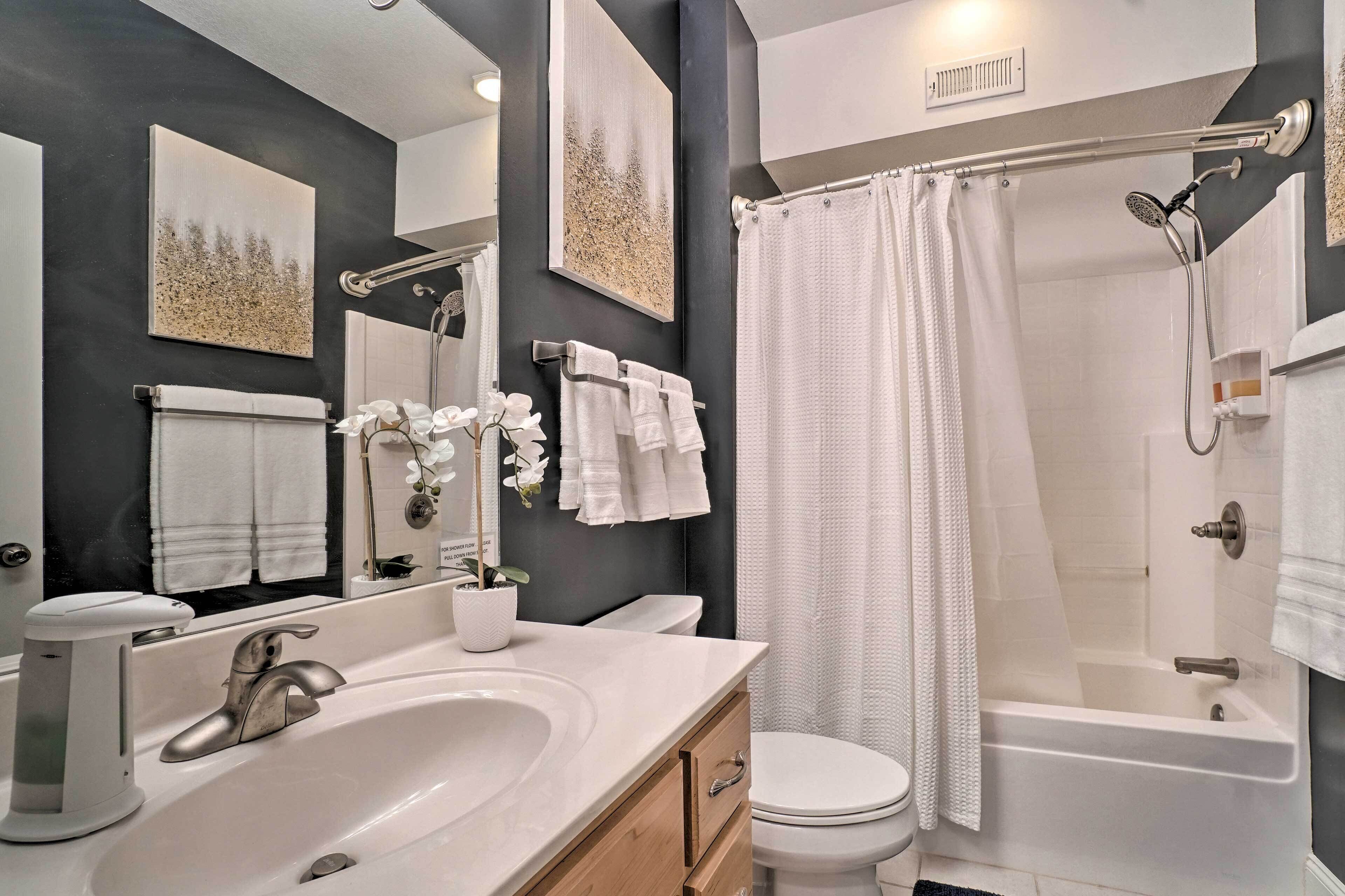 A modern bathroom with a bathtub, a shower, a sink, and a toilet.