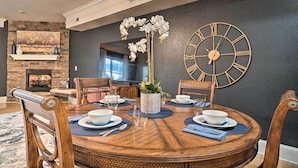 Un coin repas avec une table ronde en bois, des chaises et une grande horloge murale.