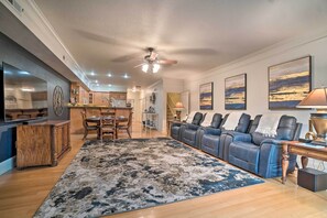 A spacious living room with a large blue sofa, a wooden coffee table, and a dining area with a wooden table and chairs.