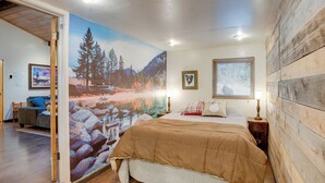 A bedroom with a large mural, a wooden headboard, a bed with a brown blanket, and a nightstand with a lamp. - Tahoe Home 3 Mi to Heavenly Mountain Resort! (Stateline)