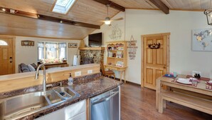 A cozy kitchen with wooden beams, a skylight, a stone wall, and a dining area with a wooden table and bench. - Tahoe Home 3 Mi to Heavenly Mountain Resort! (Stateline)