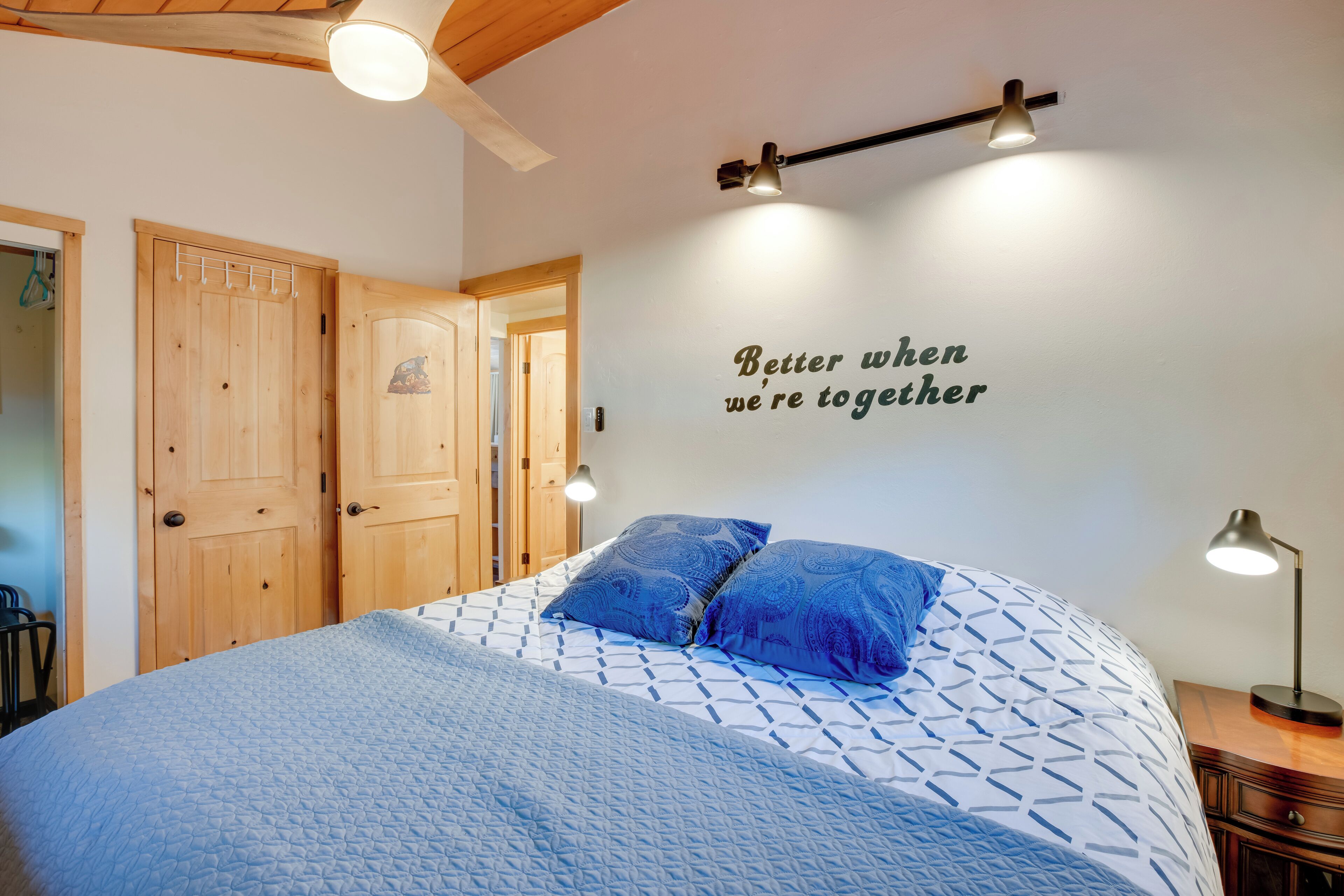 Une chambre à coucher avec un lit, un mur orné d’une citation inspirante et un ventilateur de plafond.