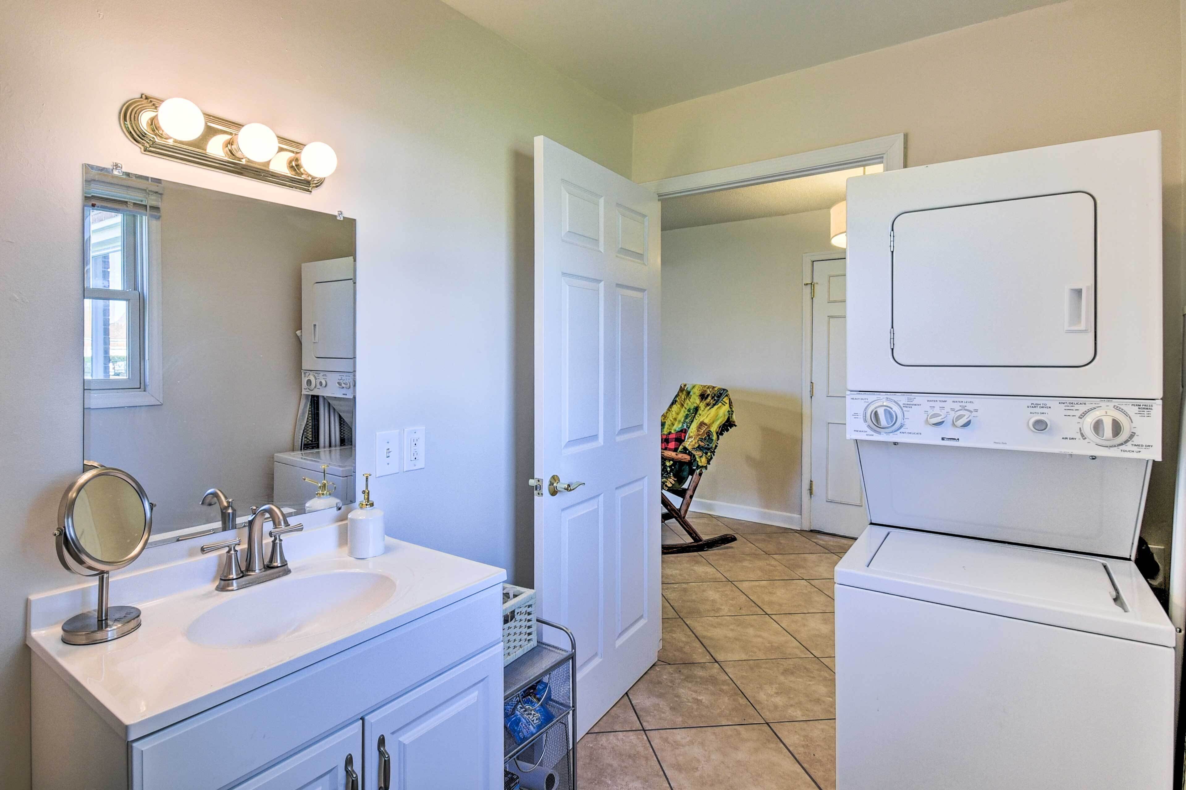 A bathroom with a sink, mirror, and a washing machine.