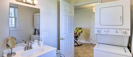 A bathroom with a sink, mirror, and a washing machine.