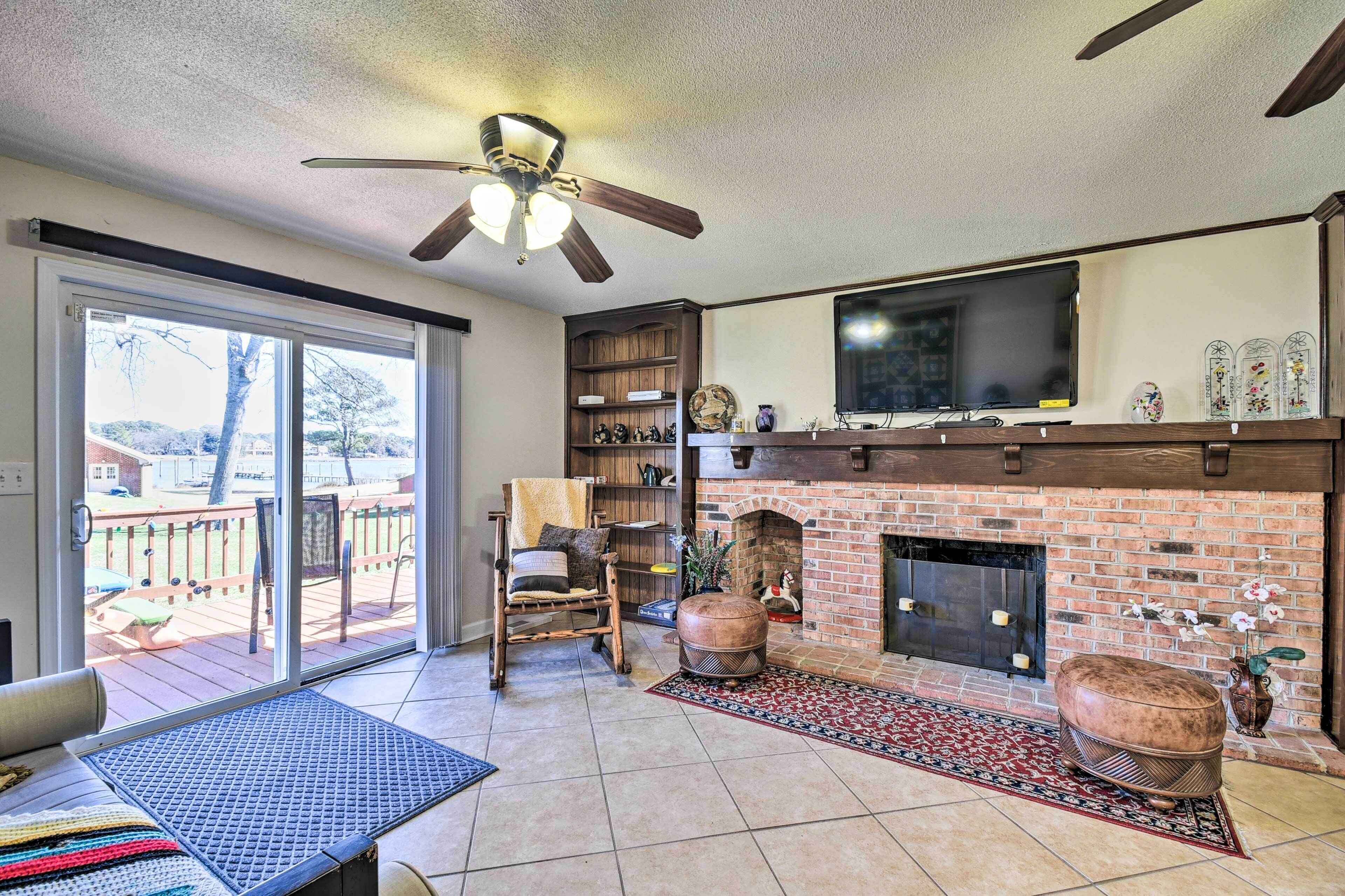 A living room with a fireplace, a television, and a ceiling fan.