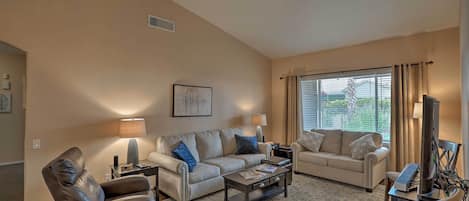 A living room with a beige sofa, a brown leather chair, a coffee table, and a TV stand.