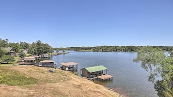 A lakeside property with several docked boats, a grassy area, and a clear view of the lake.