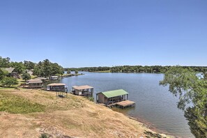 Ein Seeufergrundstück mit mehreren Booten am Steg, einer Rasenfläche und freiem Blick auf den See.