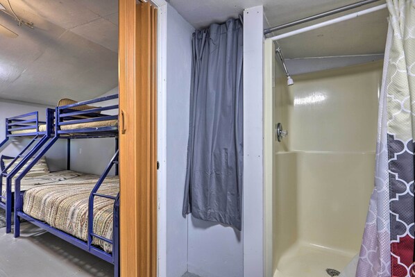 A bunk bed with a wooden door, a shower with a grey curtain, and a patterned shower curtain.