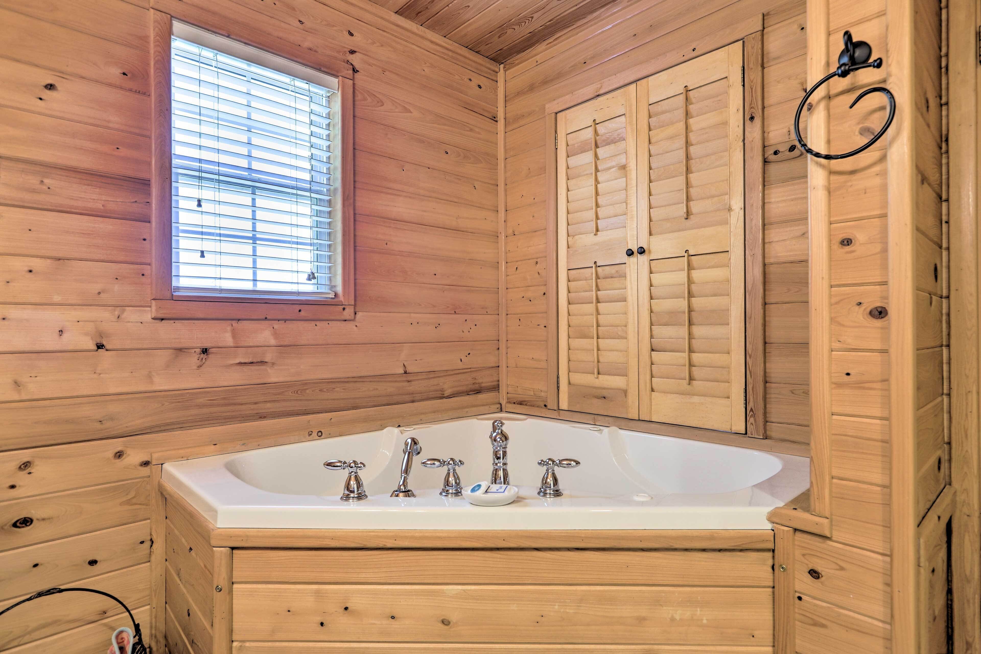 Une salle de bain rustique, avec des murs en bois, une grande baignoire, une fenêtre avec des stores et des portes en bois.