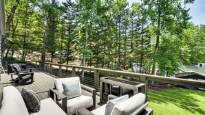 A deck with outdoor furniture, a railing, and a view of a lake and trees. - The Ultimate Luxury Retreat on Lake Burton! (Clayton)