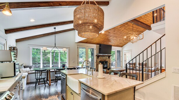 A spacious kitchen with a large island, wooden beams, and a hanging light fixture. - The Ultimate Luxury Retreat on Lake Burton! (Clayton)