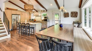 A spacious kitchen with wooden beams, a large island, and a dining area with a bench. - The Ultimate Luxury Retreat on Lake Burton! (Clayton)