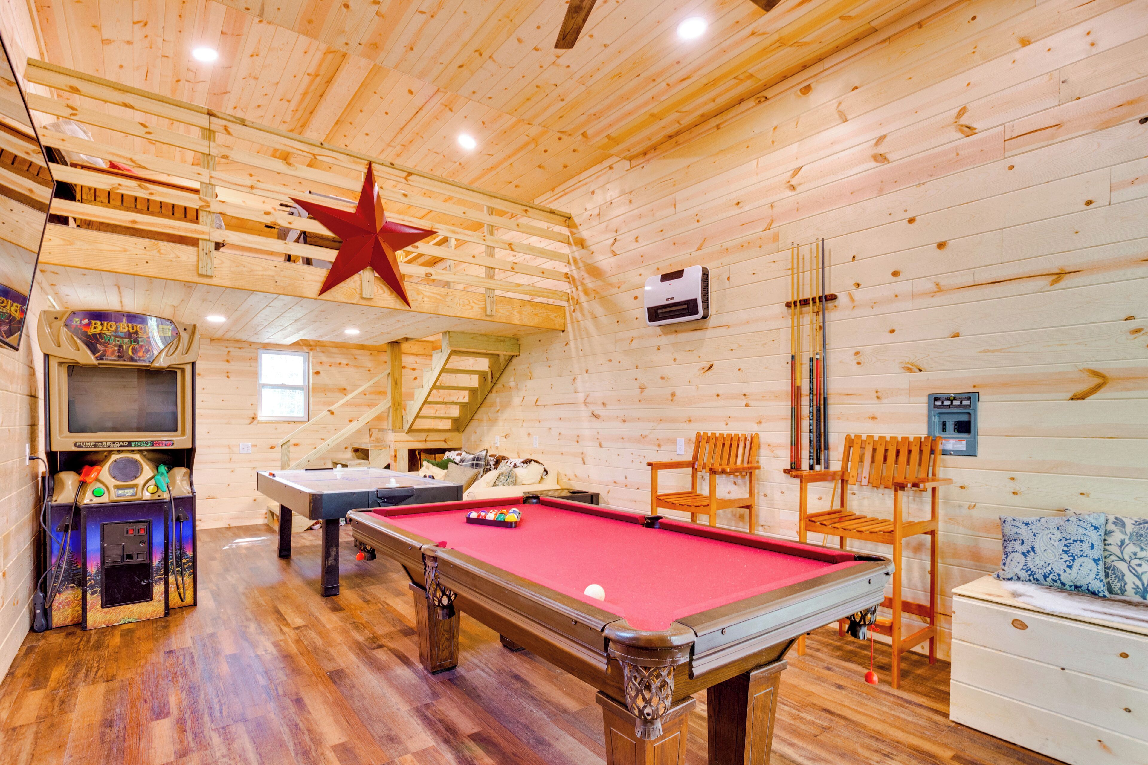 A wooden room with a pool table, a red star decoration, and a billiards table.