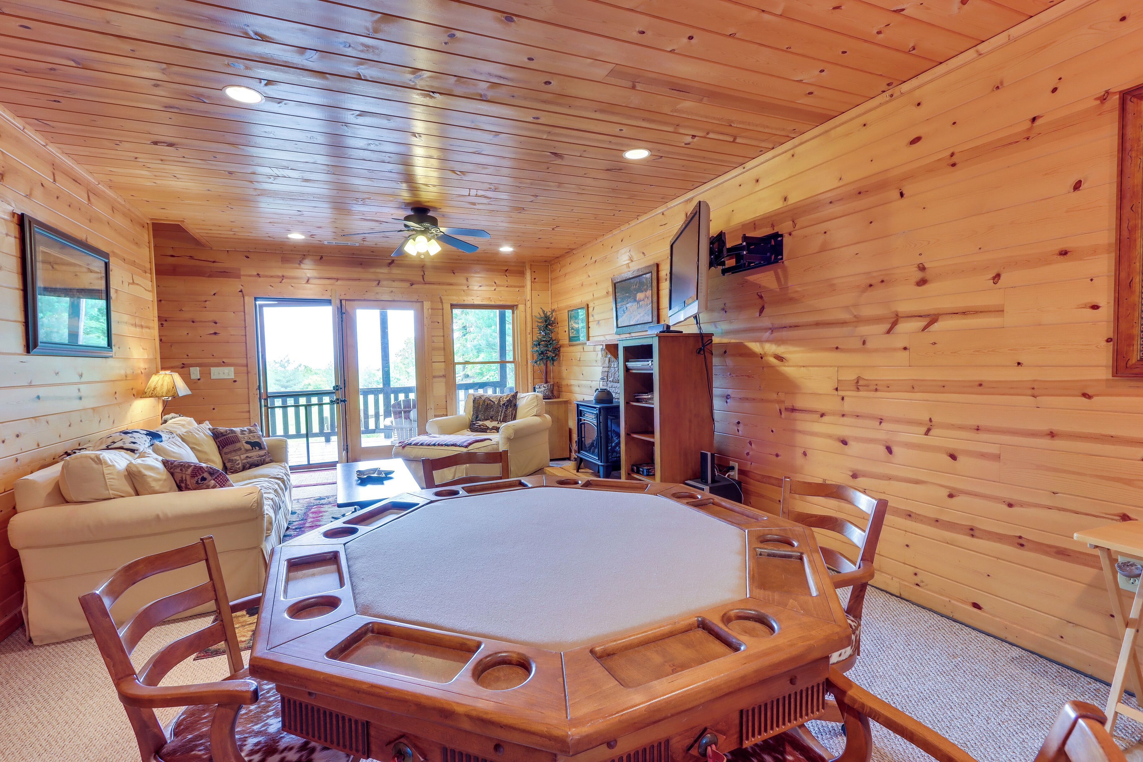 L’intérieur d’un chalet en bois comprend une grande table octogonale, un canapé et un téléviseur.