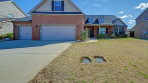 A two-story house with a brick facade, two garage doors, and a well-maintained lawn with two manhole covers. - Spacious Kathleen Vacation Rental w/ Fireplace (Kathleen)