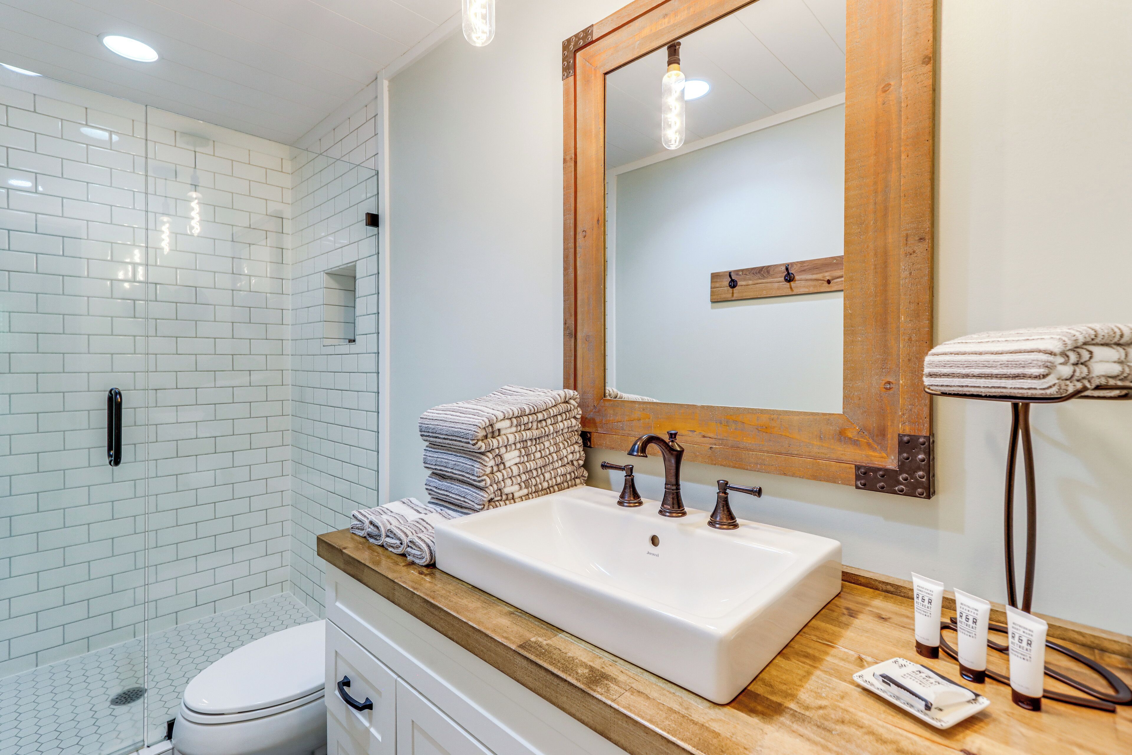 A modern bathroom with a white sink, wooden vanity, and a large mirror.