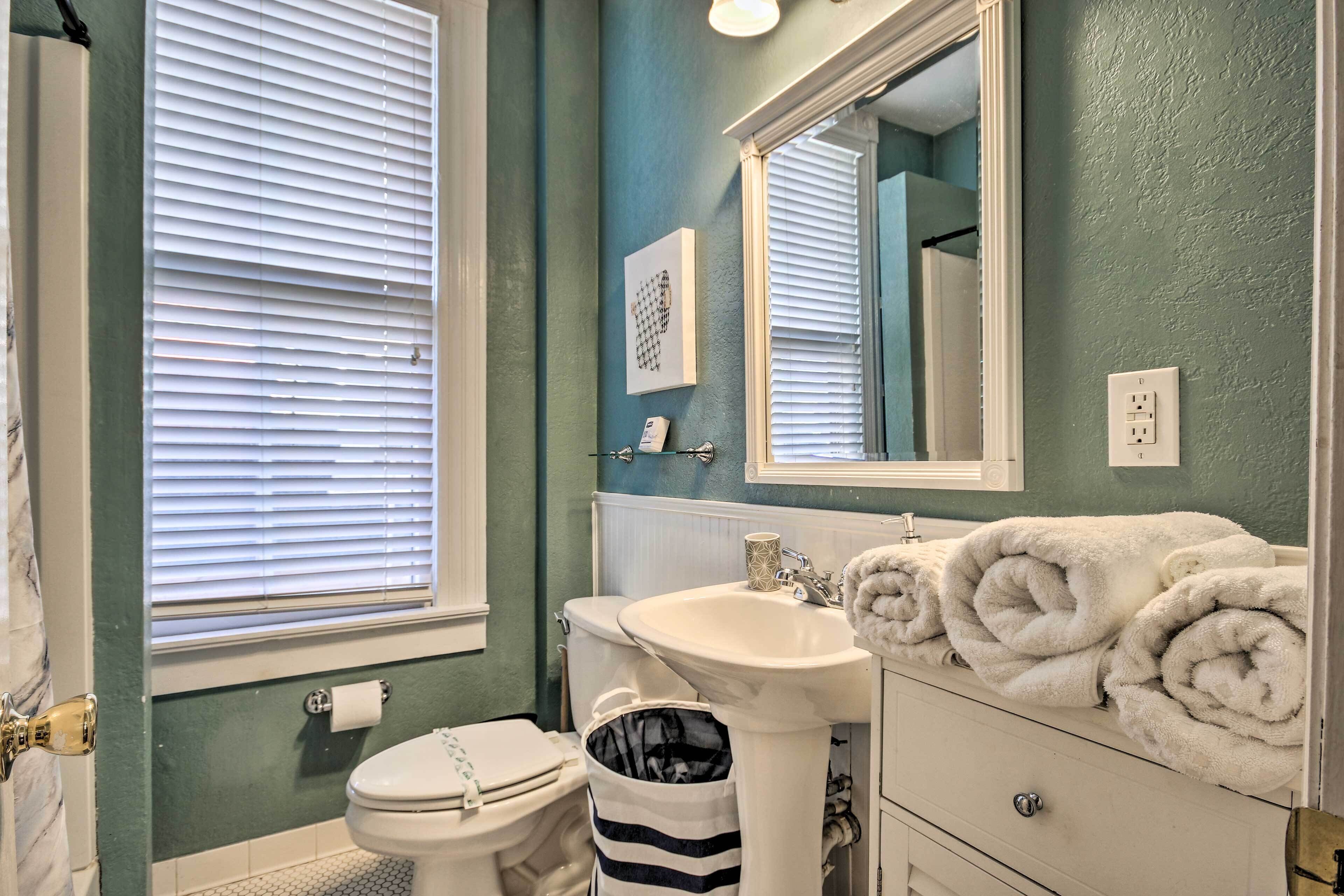 Une salle de bain avec des toilettes, un lavabo et un miroir. Il y a des serviettes sur le comptoir et une poubelle.