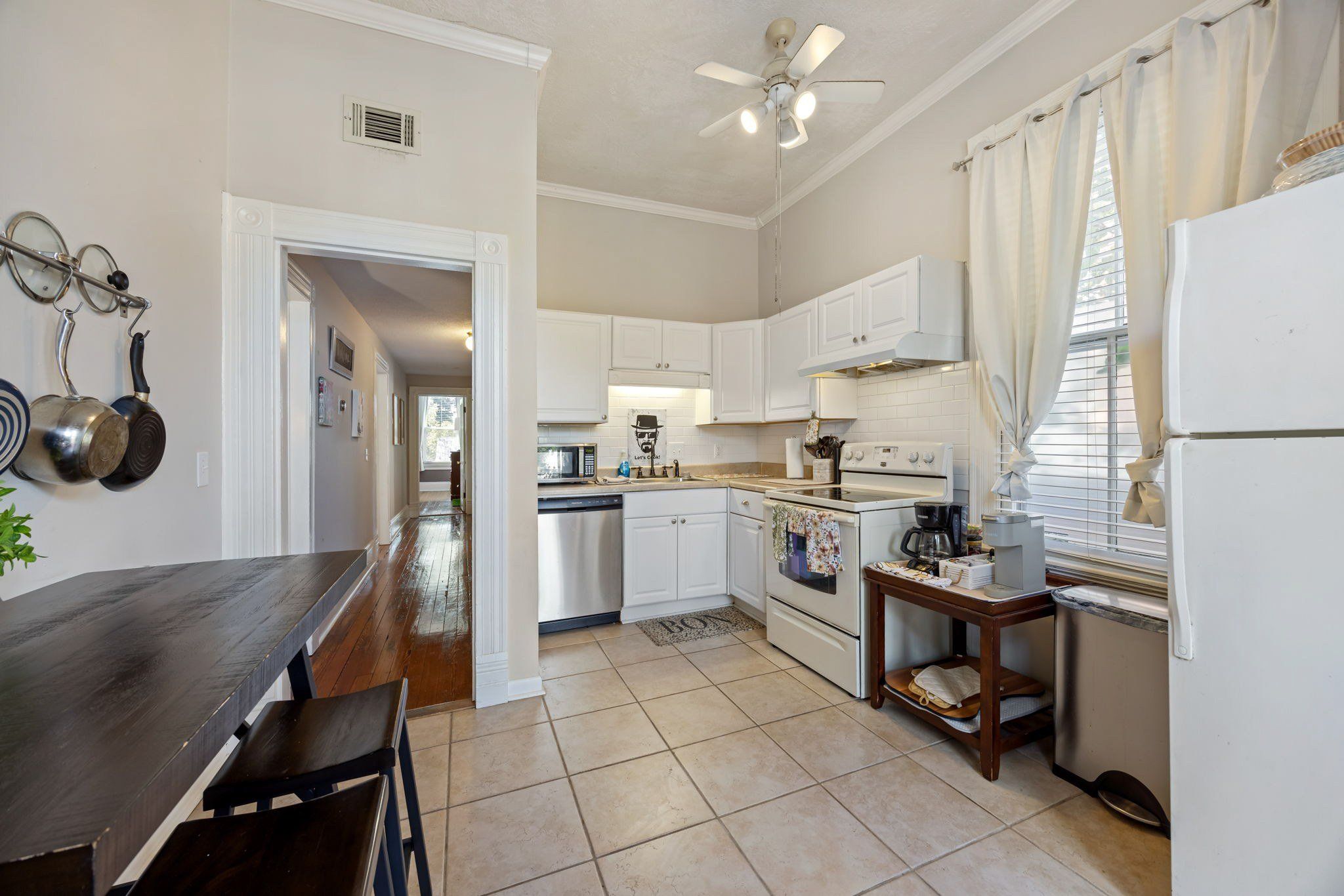 A kitchen with white cabinets, a stove, a microwave, and a ceiling fan.