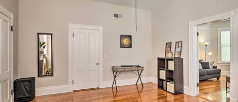 A spacious living room with hardwood floors, a ceiling fan, a small table, and a bookshelf.