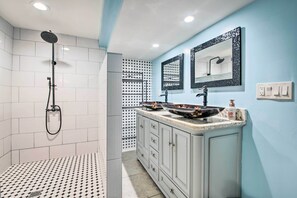 A bathroom with a shower, a sink with a mirror, and a tiled floor.