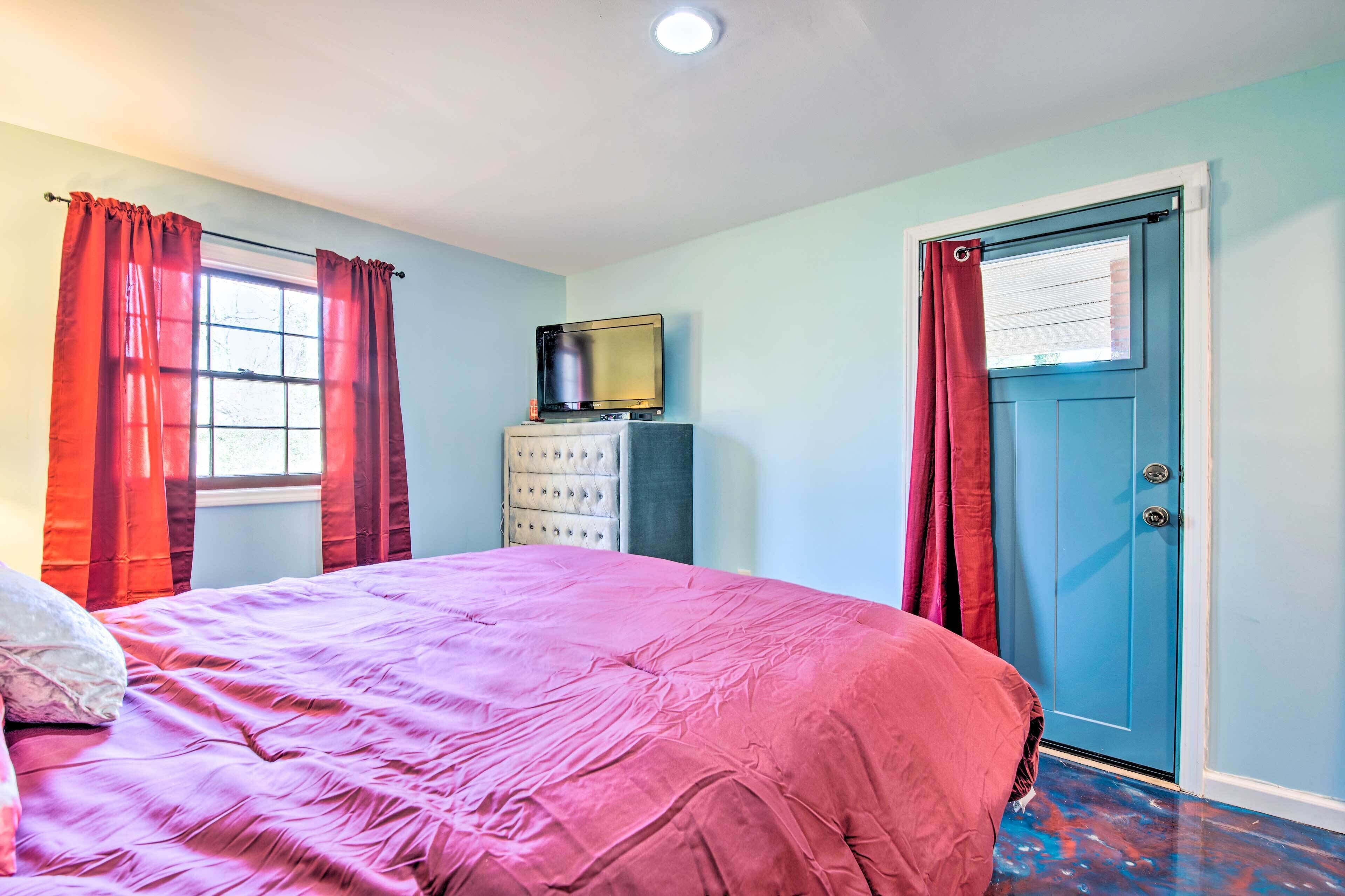 A bedroom with a bed, a dresser, a television, and a door.