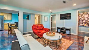 A modern living room with a red sofa, white armchairs, and a coffee table. There is a kitchen area visible in the background. - Decatur Apartment w/ Tennis Court ~ 11 Mi to ATL (Decatur)