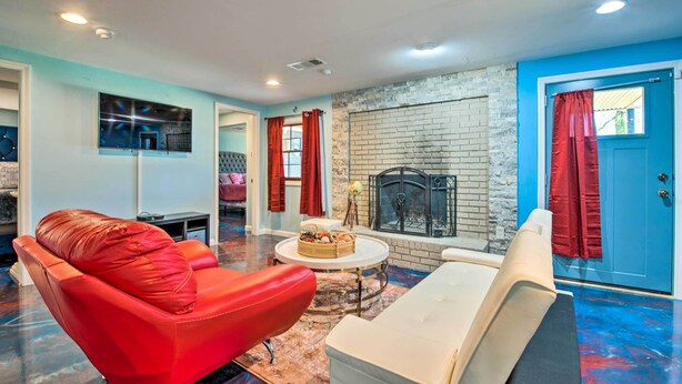 A living room with a red leather sofa, a white armchair, and a small round table with a basket. A fireplace is visible in the background, and the room has a blue accent wall. - Decatur Apartment w/ Tennis Court ~ 11 Mi to ATL (Decatur)