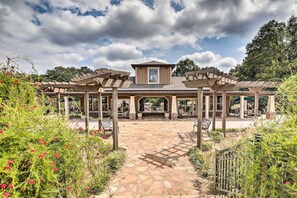 A covered patio area with a stone pathway leading to a building entrance, surrounded by greenery and a pergola structure. - Lake Allatoona Area Studio w/ Pool and Views! (Cartersville)