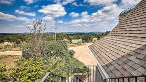 Blick vom Balkon auf einen angelegten Garten bei blauem Himmel.