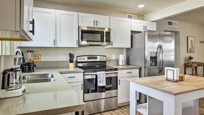 A modern kitchen with white cabinets, stainless steel appliances, and a wooden countertop. - Lovely Tucson Home ~ Walk to Reid Park Zoo! (Tucson)