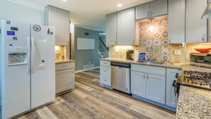 A modern kitchen with grey cabinets, a stainless steel dishwasher, and a built-in oven.