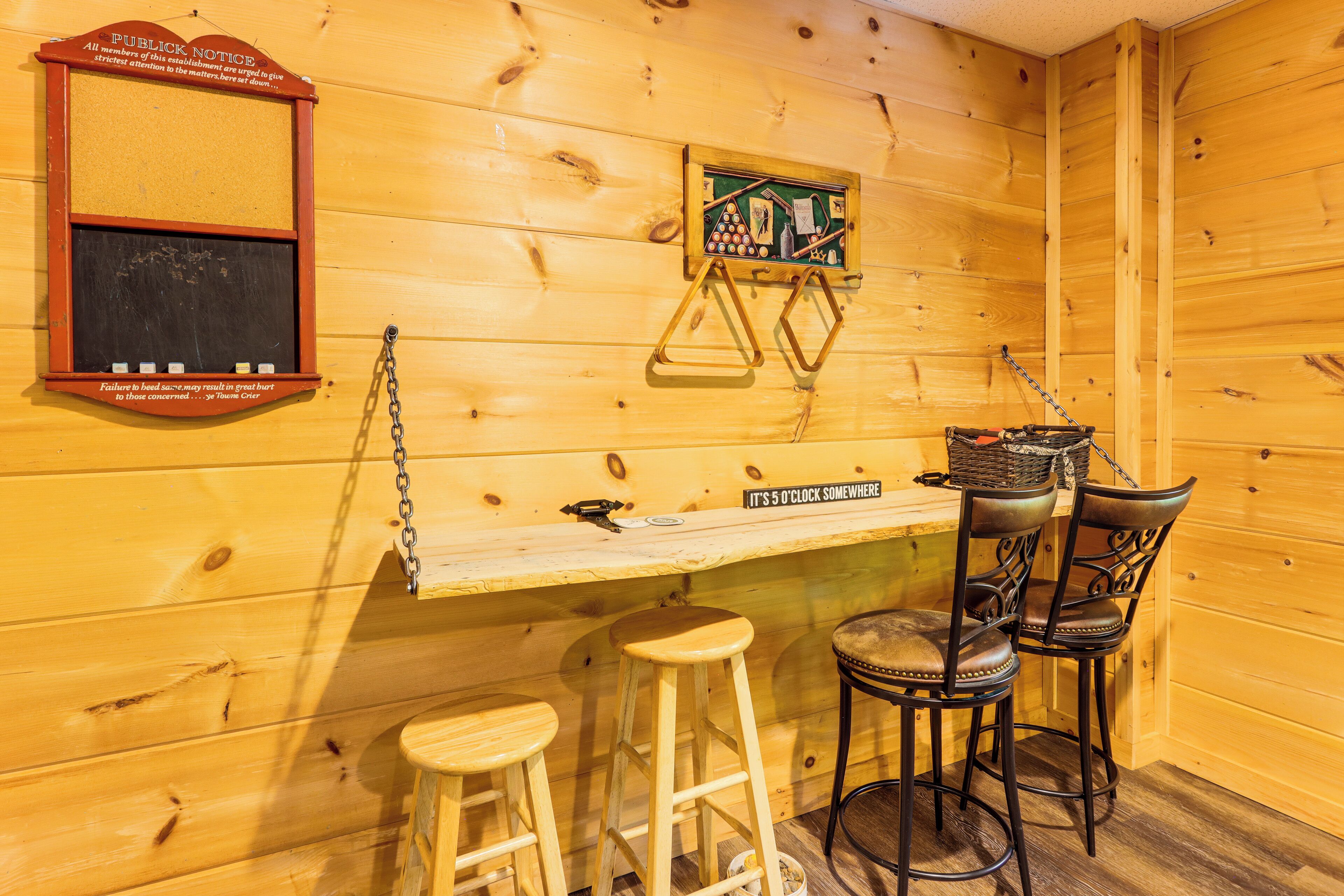 A wooden interior with a chalkboard, a framed picture, and a bar area with stools.